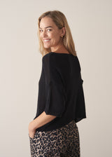 Woman wearing black short sleeve fine knit sweater and leopard print trousers