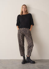 Woman wearing black short sleeve fine knit sweater and leopard print trousers