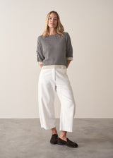 Woman wearing navy and white stripe light knitted sweater and white barrel leg jeans