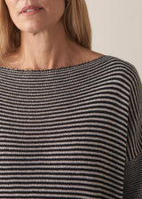 Woman wearing navy and white stripe light knitted sweater and white barrel leg jeans
