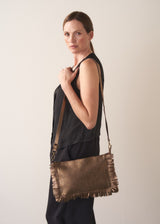 Bronze-coloured leather clutch bag with fringe details on a light gray background