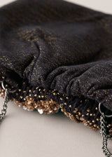 Close up of the back of a gold sequin embellished clutch bag