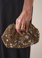 Close up of woman holding a gold sequin embellished clutch bag