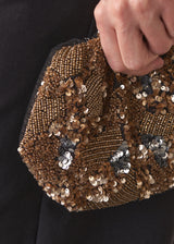Close up of woman holding a gold clutch bag embelished with sequins and beads