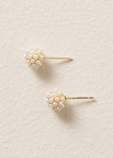 Pair of gold earrings with pearl-like stones on a beige background