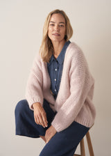 Woman wearing a navy blue short-sleeve linen shirt and linen wide-leg trousers with oversized chunky knit cardigan