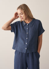 Woman wearing a navy blue short sleeve linen shirt and linen wide leg trousers