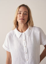 Woman wearing a short sleeve button up white boxy linen shirt