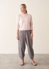 Woman wearing light blush pink boxy knitted sweater with checked barrel leg trousers