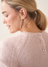 Woman wearing light blush pink boxy knitted sweater with checked barrel leg trousers