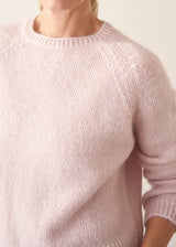 Woman wearing light blush pink boxy knitted sweater with checked barrel leg trousers