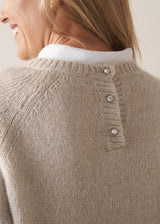Woman wearing a beige boxy sweater with navy cotton trousers