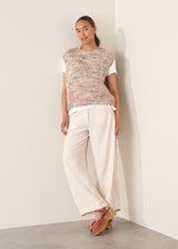 Woman wearing space dye knitted vest top with white t-shirt and light trousers