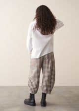 Model wearing neutral check barrel leg trousers and a white shirt