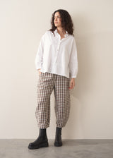 Model wearing neutral check barrel leg trousers and a white shirt