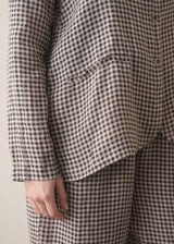 Close up of a woman modelling a grey and black checked linen jacket with matching barrel leg linen checked trousers