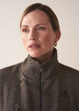 Close up of zip detail of woman wearing brown herringbone bomber jacket with sequin embelishment