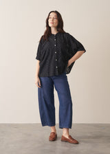 Woman wearing black broderie anglaise boxy shirt with blue jeans