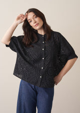 Woman wearing black broderie anglaise boxy shirt with blue jeans