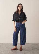 Woman wearing black broderie anglaise boxy shirt with blue jeans