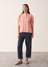 Woman wearing pink and orange gingham shirt with blue jeans