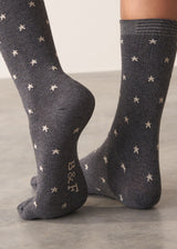 Person wearing grey cotton blend socks with metallic silver star accents and sparkle detail on the ankle, standing on a grey surface