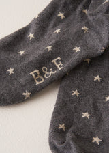 Grey cotton blend socks with metallic silver star accents and "B&F" branding on the soles, on a beige background