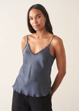 A woman wearing a midnight blue satin camisole with black trousers