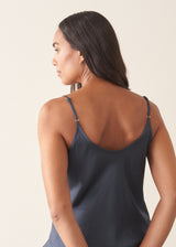 A woman wearing a midnight blue satin camisole with black trousers