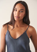A woman wearing a midnight blue satin camisole with black trousers