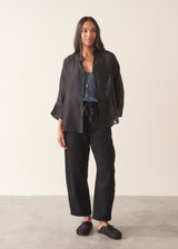 A woman wearing a midnight blue satin camisole with black trousers