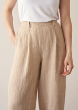 Woman wearing a white vest top and beige striped linen trousers