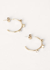 Contemporary gold stud hoop earrings with crystal detail on white background