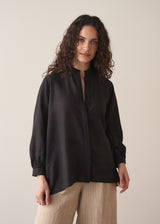 Woman wearing a black longline shirt with oatmeal linen trousers