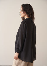 Woman wearing a black longline shirt with oatmeal linen trousers
