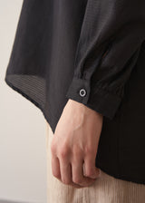 Woman wearing a black longline shirt with oatmeal linen trousers