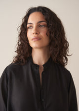 Woman wearing a black longline shirt with oatmeal linen trousers
