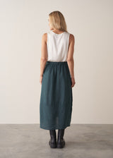 Woman wearing dark green linen cocoon skirt with grey jumper