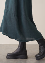 Woman wearing dark green linen cocoon skirt with grey jumper