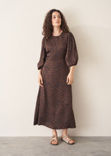 Woman wearing a brown patterned dress against a plain background