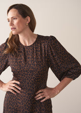 Woman wearing a round neck leopard print dress against a plain background