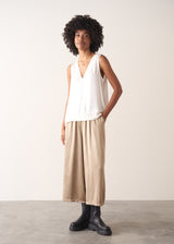 Woman wearing a white sleeveless top against a plain background