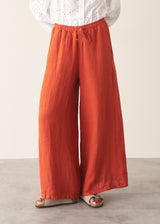 Woman wearing bright red wide leg linen trousers and white v-neck top