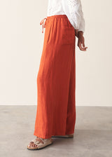 Woman wearing bright red wide leg linen trousers and white v-neck top