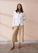 Women wearing a fluid white crepe button up shirt with pocket details, styled with neutral trousers and heels