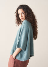 Woman wearing teal knitted sweater and rust red linen trousers