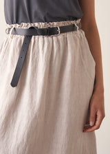 Woman wearing grey tank top and neutral linen midi skirt
