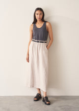 Woman wearing grey tank top and neutral linen midi skirt