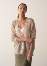 Woman wearing a beige cardigan against a plain background