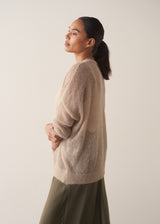 Woman wearing a beige cardigan against a plain background